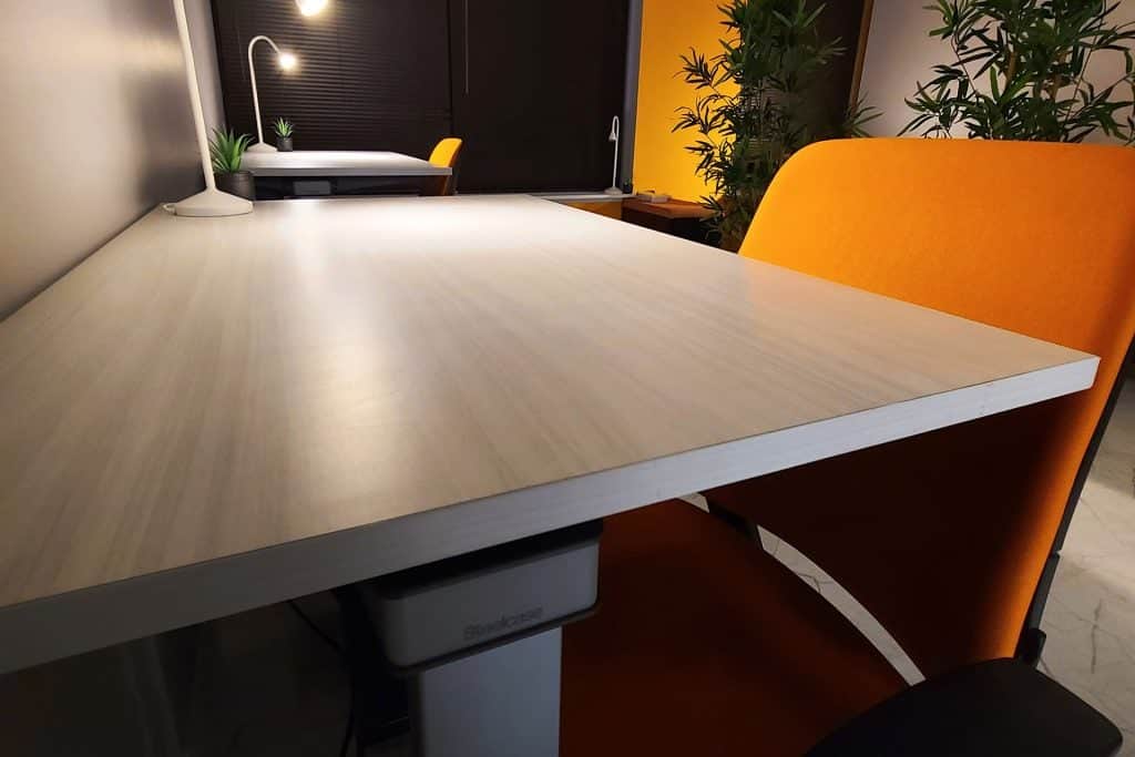 dedicated desk workspace with plants, lights, orange seats, and standing desk